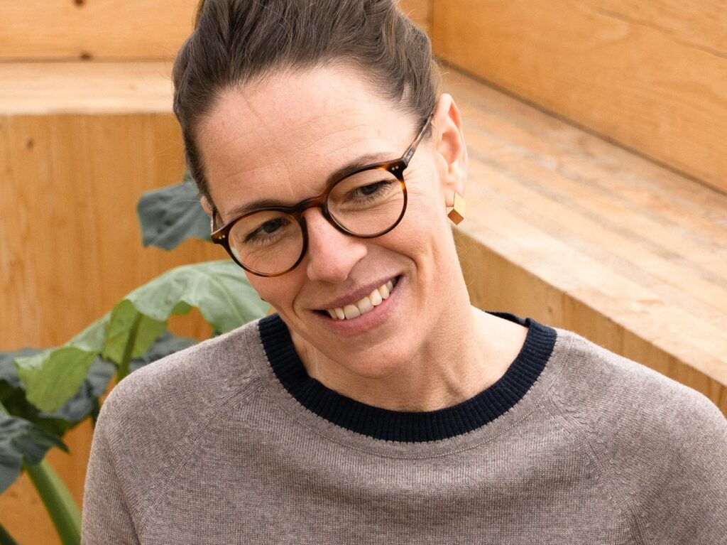 Portrait of smiling woman with glasses. Products can be seen in the background.