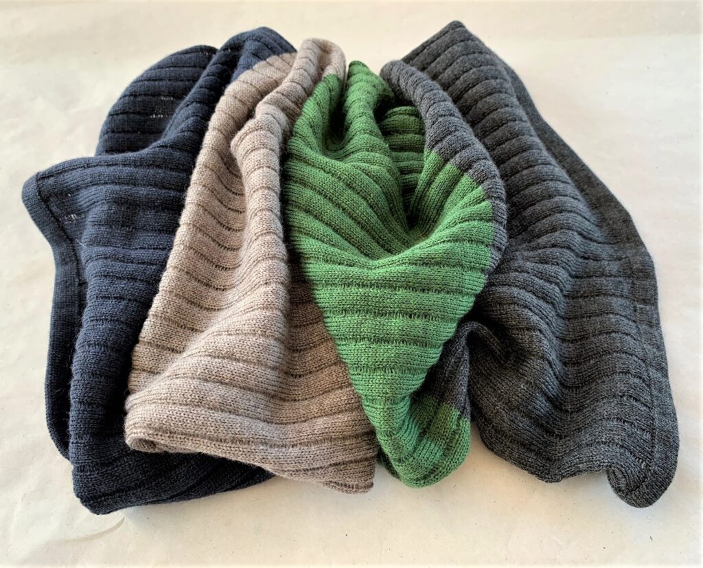 Folded knitted products in blue, beige, green, and gray colors.